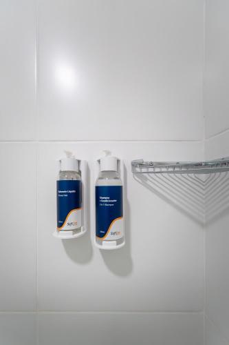two bottles ofodorizers on a shelf in a bathroom at Soft Inn Alagoinhas in Alagoinhas