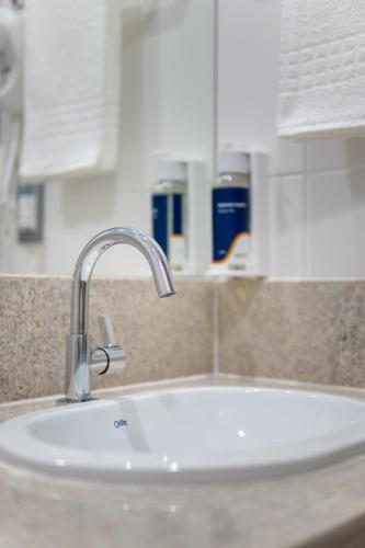 a bathroom sink with a faucet on a counter at Soft Inn Alagoinhas in Alagoinhas