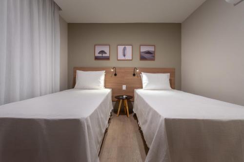 two beds sitting next to each other in a room at Soft Inn Alagoinhas in Alagoinhas