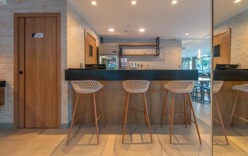 a kitchen with a black counter and stools at Soft Inn Alagoinhas in Alagoinhas