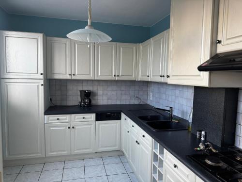 a kitchen with white cabinets and a black counter top at Chambre avec lit rond insolite proche gare TGV in Lamballe Armor