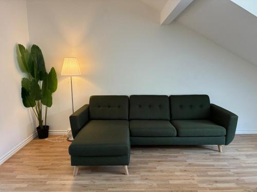 a green couch in a living room with a lamp at Central city apartment with parking space in Hjørring