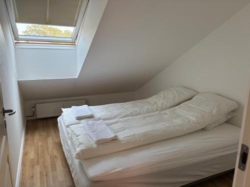a white bed in a room with a window at Central city apartment with parking space in Hjørring