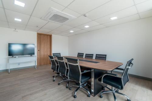 a conference room with a table and chairs and a flat screen tv at Soft Inn Alagoinhas in Alagoinhas