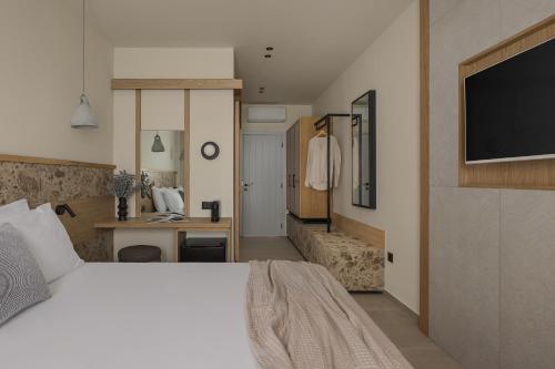 Un dormitorio con una cama, un escritorio y un televisor. en Lumora Suites, en Kavos
