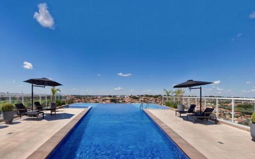 a swimming pool with chairs and umbrellas on a building at Estúdio Duo JK - Conforto, segurança e modernidade in Sao Jose do Rio Preto