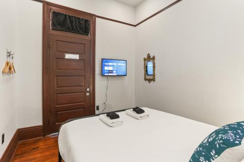 a bedroom with a bed with a tv on the wall at Site 61 Guesthouse in New Orleans