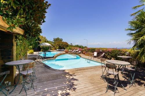 a deck with tables and chairs and a swimming pool at Villa Massimo Cartaromana with wide pool and view on the Castle in Ischia