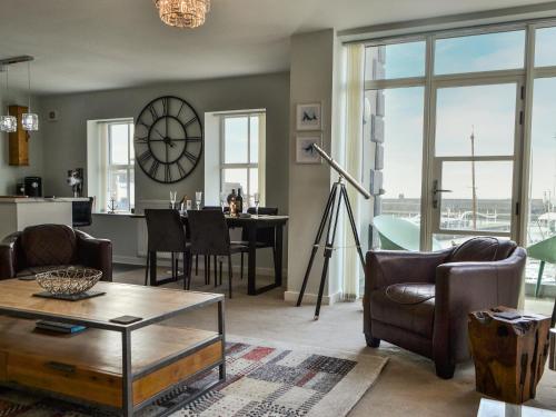 a living room with a table and a clock on the wall at Quayside7 in Whitehaven