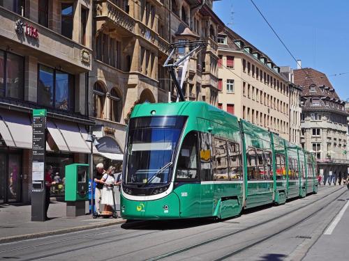 a green bus driving down a city street at Studio Breiti mit separatem Eingang in Pratteln