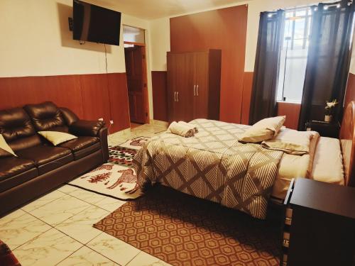 a bedroom with a bed and a leather couch at Casa Mirador guesthouse in Cusco