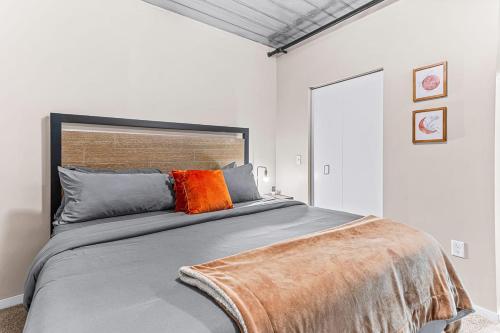 a bedroom with a large bed with an orange pillow at 6 Modern Apts - 12 Beds w Parking - Near Kerrytown in Ann Arbor