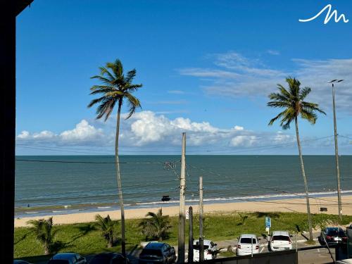a view of a beach with palm trees and the ocean at Beach Haus in Tambaú