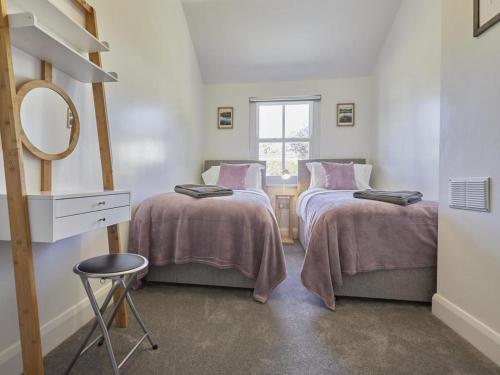 Un dormitorio con dos camas y un espejo y un taburete. en 2 Bed in Keswick SZ011, en Keswick