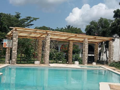 a swimming pool with a wooden pergola over it at Fred Hunter Villa in Tiwi