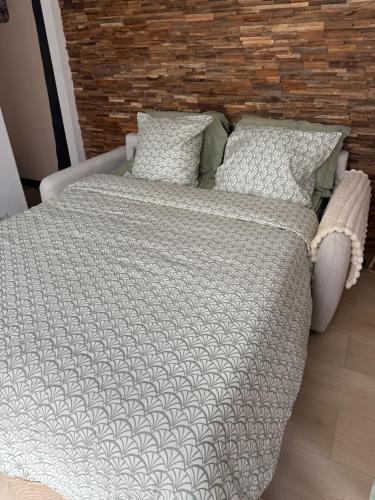 a bed with a comforter and two pillows at Chic et confort à deux pas de tout in Nevers
