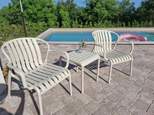 two white chairs sitting next to a swimming pool at Villa One in Jastrebarsko