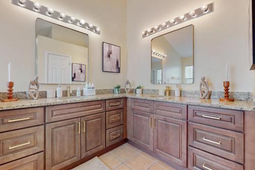 a bathroom with two sinks and two mirrors at Cumbrian Lakes Villa in Kissimmee