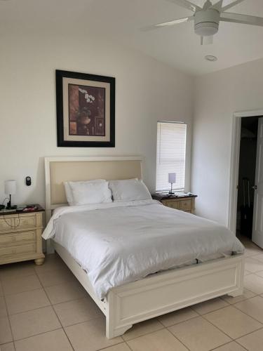 a bedroom with a white bed and a ceiling fan at Punta Gorda Home, Sleeps 10 in Punta Gorda