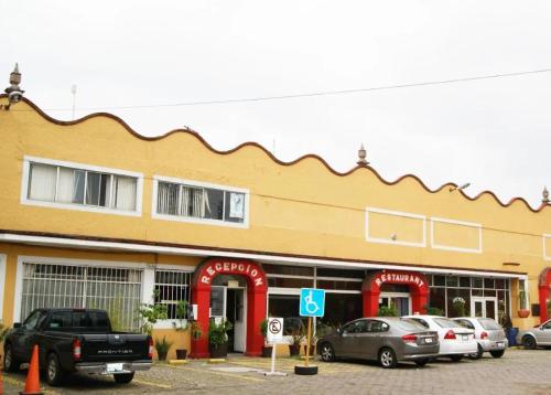 a building with cars parked in a parking lot at Hotel Árbol Grande in Morelia