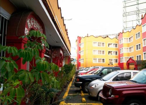 a row of cars parked in a parking lot next to buildings at Hotel Árbol Grande in Morelia