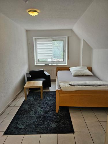 a bedroom with a bed and a chair and a window at Waldeslust Pension in Oelde