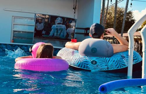 a man and a woman on inflatables in a swimming pool at Villa Las Olas Designed with you in mind! in Fort Lauderdale
