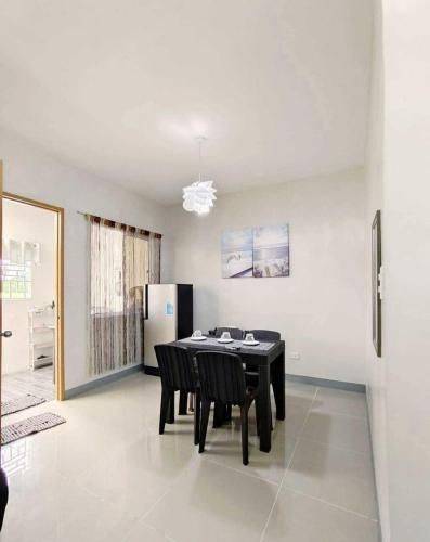 uma sala de jantar com uma mesa preta e cadeiras em Wonderfully cozy apartment em Tagum