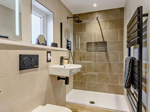 a bathroom with a sink and a toilet and a shower at 4 Bed in Weybourne 91228 in Weybourne