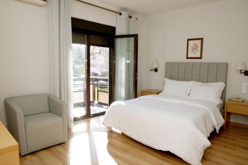 ein Schlafzimmer mit einem großen weißen Bett und einem Stuhl in der Unterkunft Hotel Ribadouro in Alijó