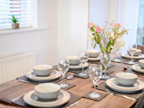 a table with plates and glasses and a vase of flowers at 4 Bed in Brockenhurst 80420 in Brockenhurst