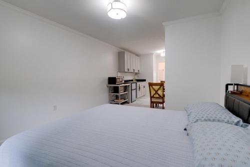 a bedroom with a white bed and a kitchen at Dock Access Waterfront Studio in Colonial Beach! in Colonial Beach
