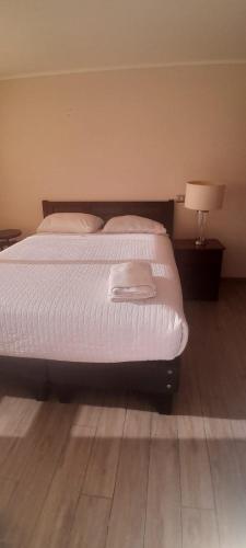 a bed in a bedroom with a lamp on a wooden floor at Departamento Central Vip in Antofagasta
