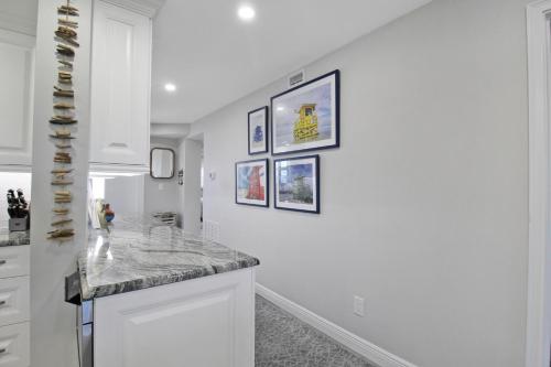 a white kitchen with pictures on the wall at Luxurious 2BR Gulfview Condo On Siesta Key Steps To The Beach Gulf Horizon in Sarasota