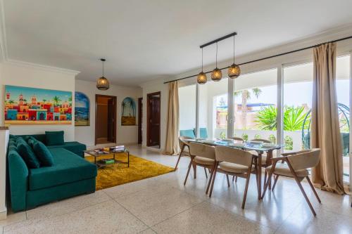 a living room with a green couch and a table and chairs at Ocean Breeze Retreat Steps from the Tiznit Shore in Tamellalt