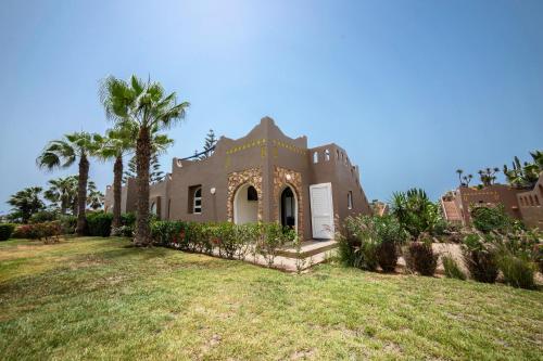 a large house with palm trees in a yard at Ocean Breeze Retreat Steps from the Tiznit Shore in Tamellalt