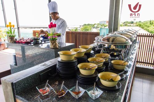 a chef standing behind a buffet with bowls and plates at Kroque Boutique & Bistro in Ang Sila