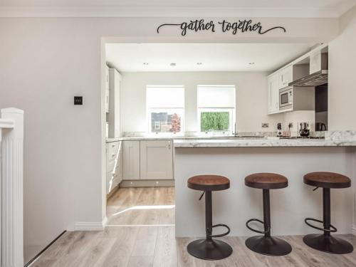 a white kitchen with two stools at a counter at The White House in Callander