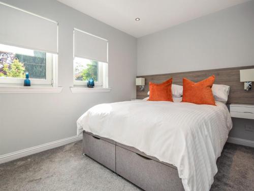 a white bedroom with a large bed with orange pillows at The White House in Callander