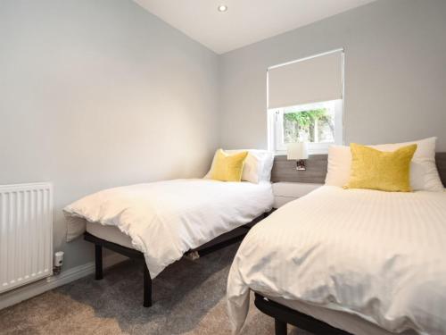 two beds with yellow pillows in a bedroom at The White House in Callander