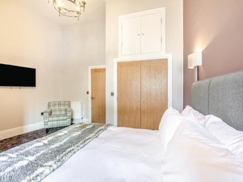 a bedroom with a white bed and a tv at The Embassy in Eyemouth