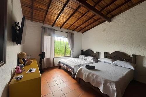 a bedroom with two beds and a table and a window at Exclusiva cabaña el lago- Naturaleza in Chinácota