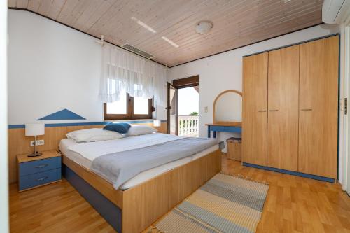 Un dormitorio con una cama grande y un armario de madera. en Apartments Villa Verica - Mit Meerblick & Pool auf der Insel Rab, en Banjol