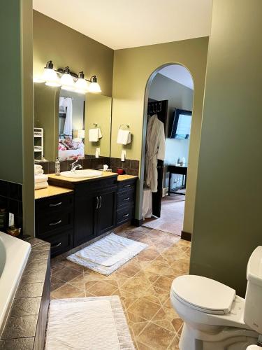 a bathroom with a sink and a toilet and a mirror at Wolf Creek Bed and Breakfast in Ponoka