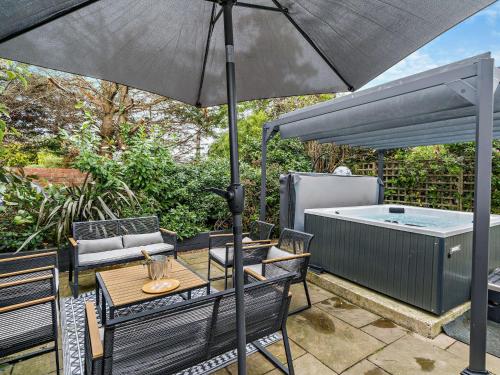 a patio with a table and an umbrella and a hot tub at 4 Bed in Hayton SZ119 in Hayton