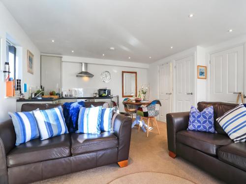 a living room with two leather couches and a kitchen at The Lodge in Carlyon Bay