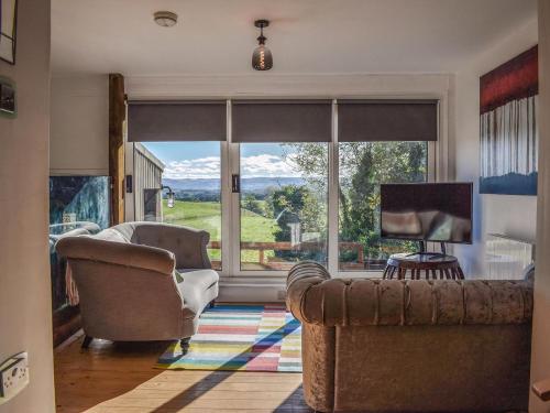 a living room with a couch and a large window at Daisybank Cottage in Crieff