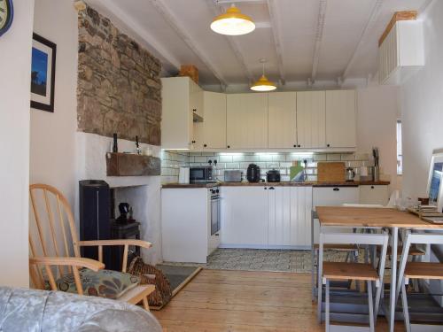 a kitchen with white cabinets and a wooden table at Daisybank Cottage in Crieff