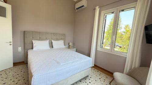 a bedroom with a white bed and a window at Magdalini Garden House in Paralion astros