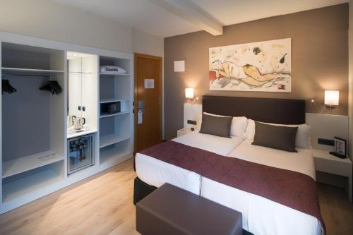 バルセロナにあるカタロニア カステルノウの大きなベッドとデスクが備わるホテルルームです。